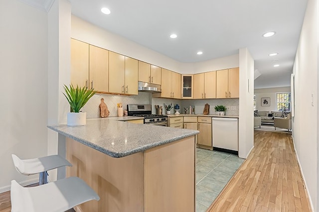 kitchen with dishwasher, light brown cabinetry, decorative backsplash, kitchen peninsula, and stainless steel range with gas cooktop