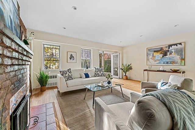 living area with a fireplace, radiator, wood finished floors, and a healthy amount of sunlight