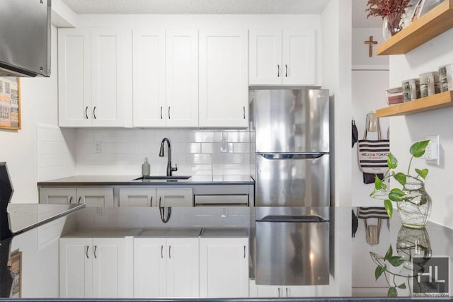 kitchen with white cabinets, a sink, and freestanding refrigerator