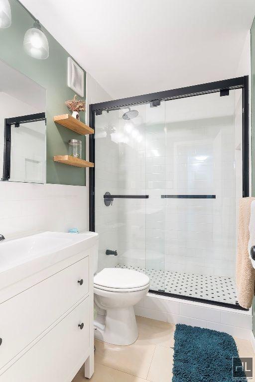 bathroom featuring visible vents, toilet, a stall shower, vanity, and tile patterned floors