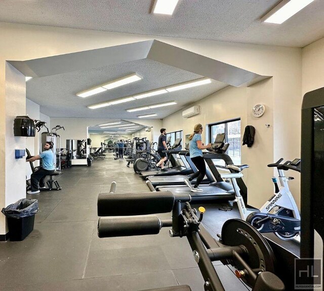 gym featuring a textured ceiling and a wall mounted AC