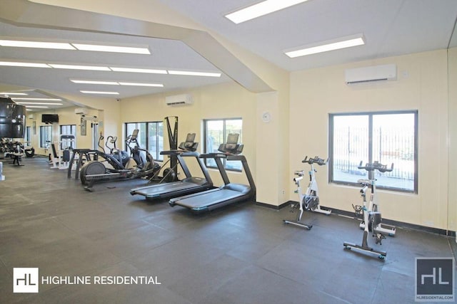 exercise room featuring a wall unit AC and baseboards