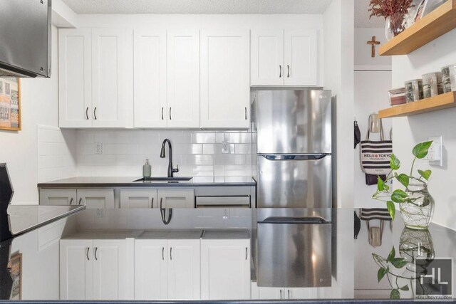 kitchen with a sink, freestanding refrigerator, and white cabinets