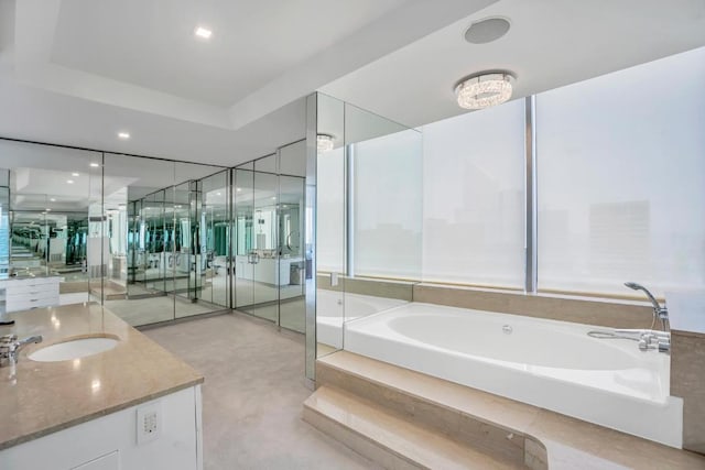 bathroom with a tray ceiling, a tub to relax in, and vanity