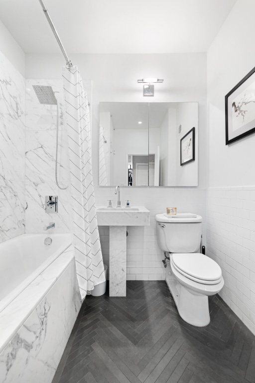 bathroom with toilet, shower / tub combo, and tile walls