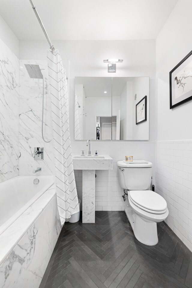 3 Hanover Sq Unit 13F, New York City, NY 10004 - full bathroom featuring a combined bath / shower with marble appearance, toilet, tile walls, and wainscoting