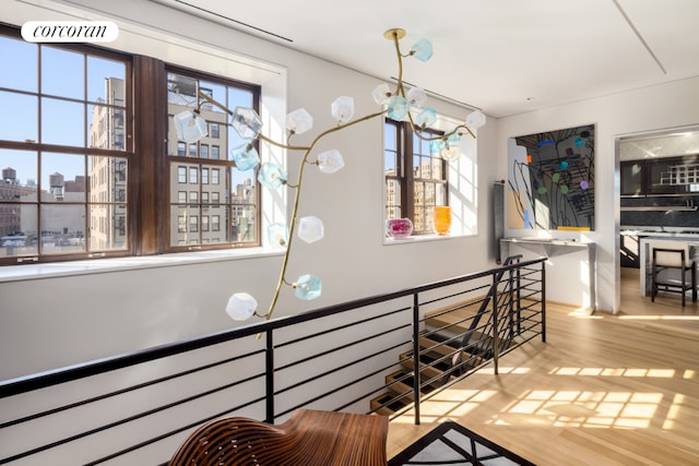 corridor featuring an inviting chandelier, a city view, an upstairs landing, and wood finished floors