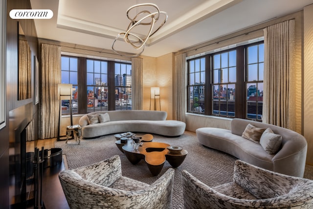 living room with an inviting chandelier, a raised ceiling, and a city view