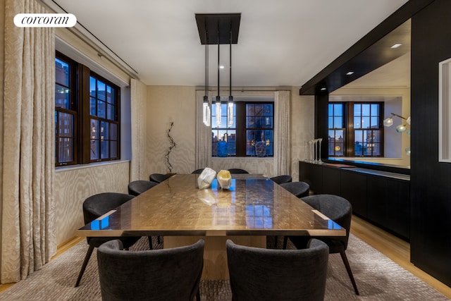 dining area with light wood finished floors and wallpapered walls