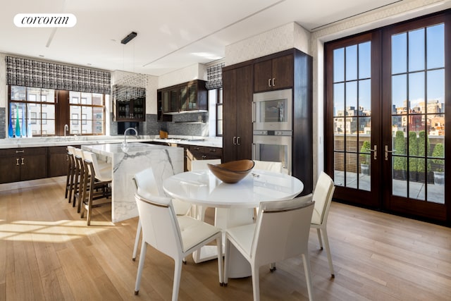 dining area with light wood-style flooring, visible vents, and french doors