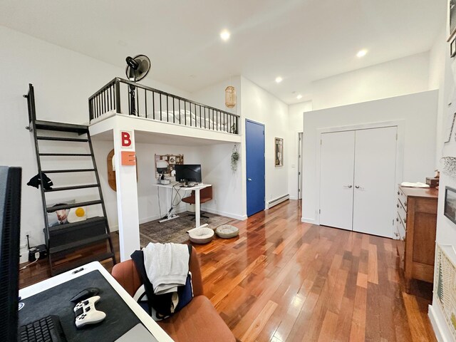 interior space with wood-type flooring and a baseboard heating unit