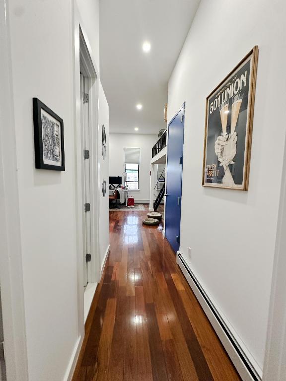 corridor with dark hardwood / wood-style flooring and a baseboard radiator