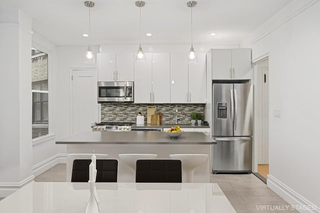 kitchen with stainless steel appliances, pendant lighting, backsplash, and white cabinetry