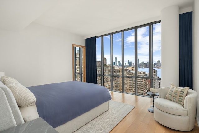 bedroom featuring expansive windows, a water view, and wood-type flooring