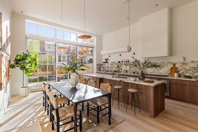 dining room featuring light wood-style flooring, a high ceiling, and ornamental molding