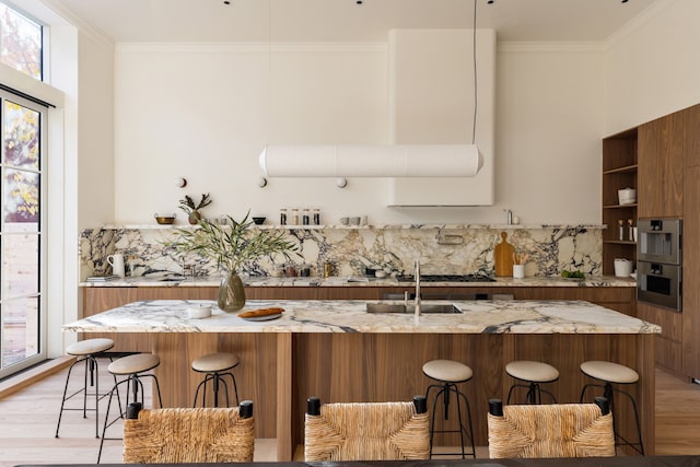 kitchen featuring brown cabinetry, backsplash, light wood-style flooring, and crown molding