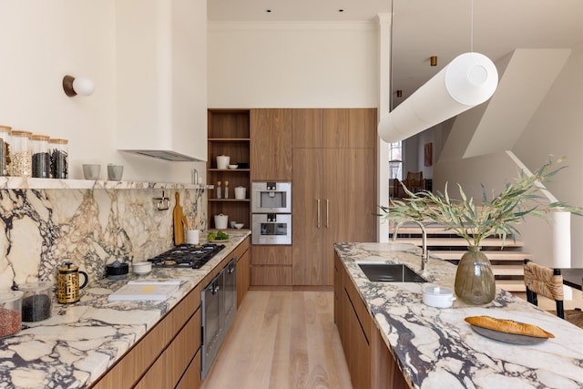 kitchen featuring light wood-style flooring, a sink, brown cabinets, modern cabinets, and crown molding