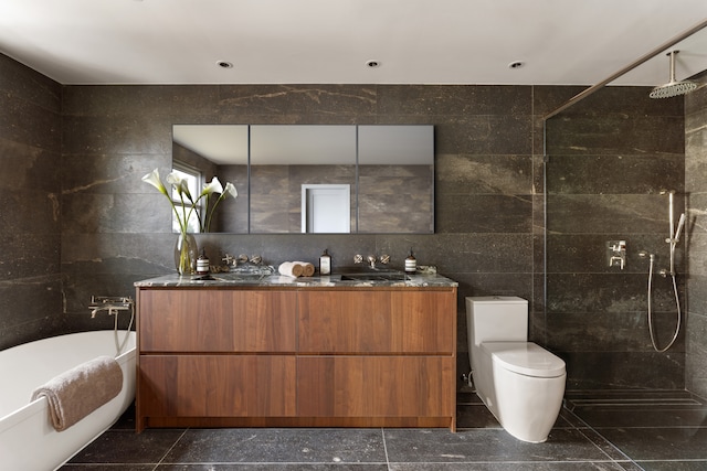 bathroom featuring double vanity, a soaking tub, walk in shower, and tile walls