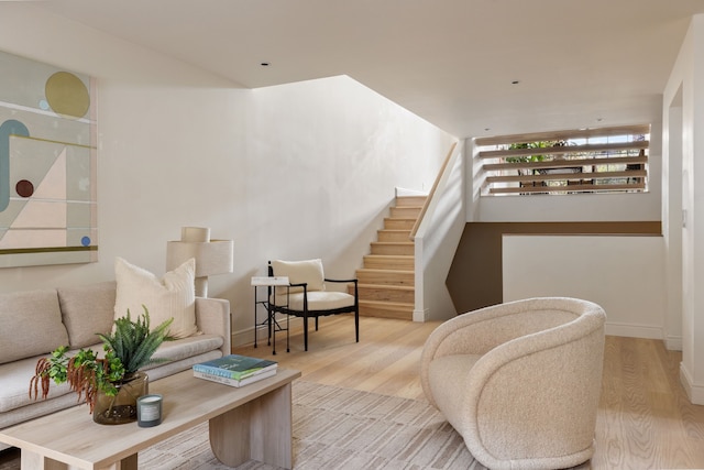 living area with baseboards, stairway, and wood finished floors