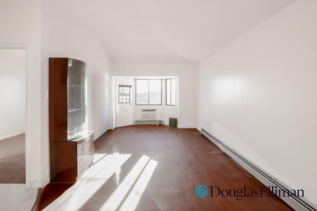 unfurnished bedroom featuring a baseboard heating unit, a closet, and dark colored carpet