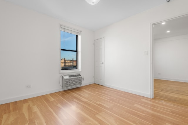 unfurnished room with recessed lighting, an AC wall unit, baseboards, and light wood finished floors