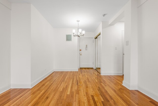 unfurnished dining area with visible vents, a notable chandelier, light wood-style flooring, and baseboards