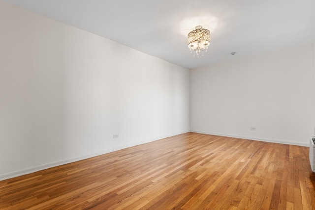 spare room with light wood-type flooring and a notable chandelier