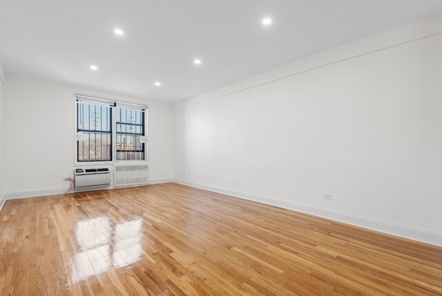 spare room with recessed lighting, radiator heating unit, baseboards, and light wood finished floors