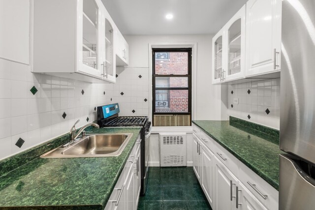 kitchen featuring stainless steel appliances, dark tile patterned flooring, dark countertops, and a sink