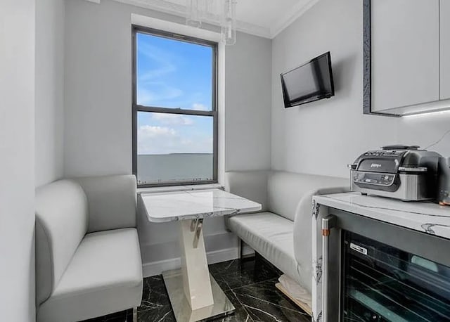 interior space with beverage cooler, baseboards, marble finish floor, ornamental molding, and breakfast area