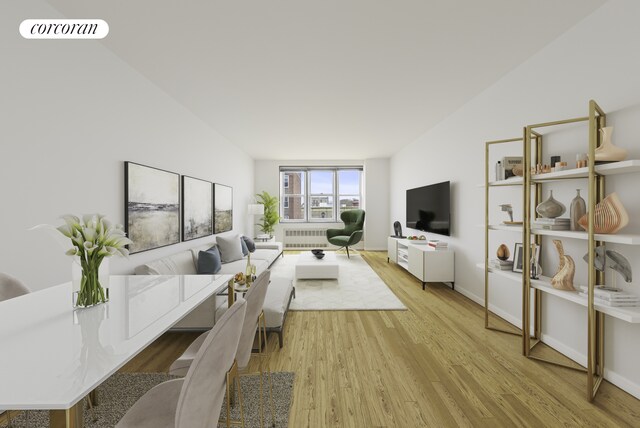 living room featuring vaulted ceiling, radiator, and light wood-type flooring