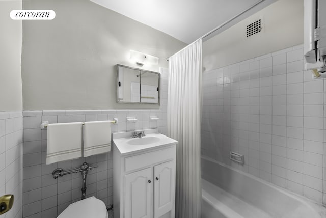 full bathroom featuring shower / tub combo, visible vents, tile walls, and vanity