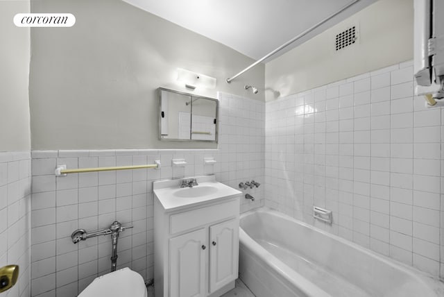 full bath featuring tile walls, visible vents, shower / bath combination, toilet, and vanity