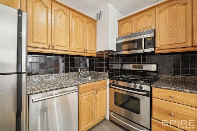 kitchen featuring dark stone countertops, sink, decorative backsplash, and stainless steel appliances