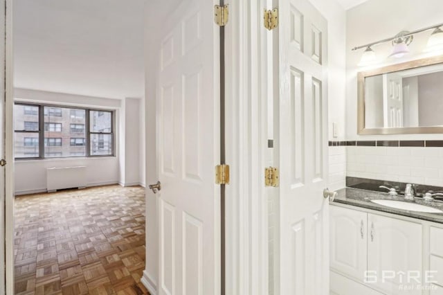 bathroom with parquet floors, vanity, and radiator