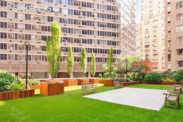 view of property's community featuring a lawn and a patio