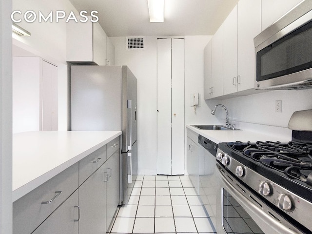 kitchen with white cabinetry, appliances with stainless steel finishes, sink, and light tile patterned floors