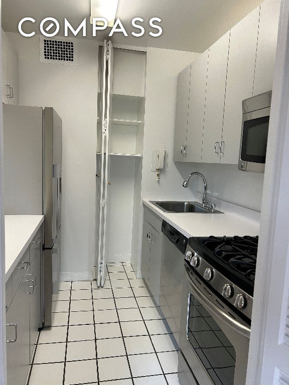 kitchen with sink, light tile patterned floors, and appliances with stainless steel finishes