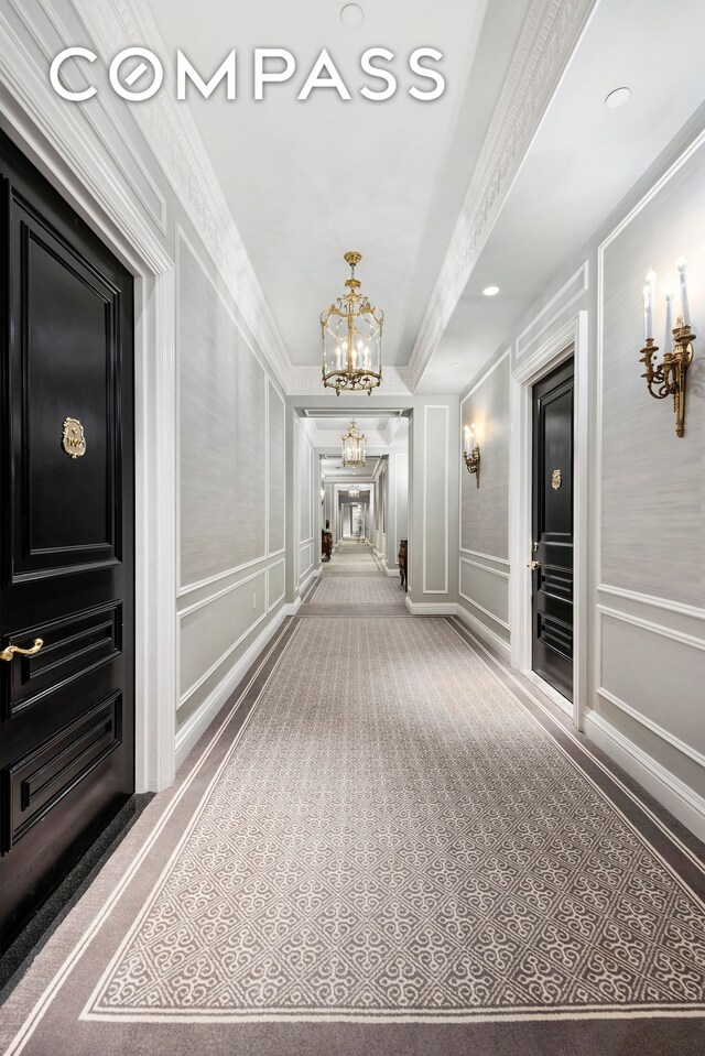 hall featuring ornamental molding and a chandelier