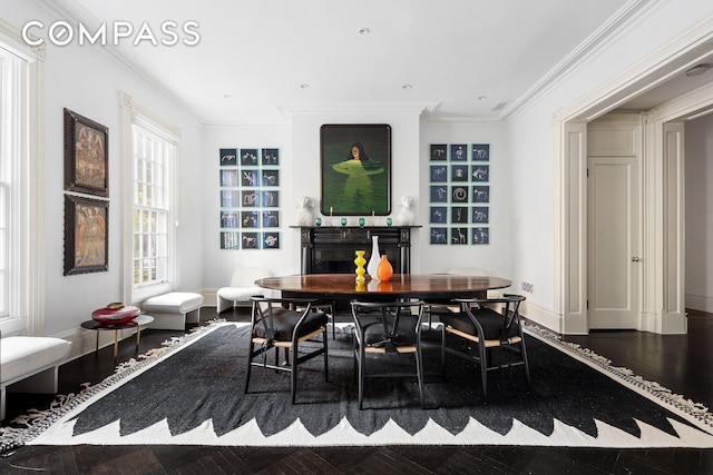 dining room with baseboards, wood finished floors, a fireplace, and crown molding