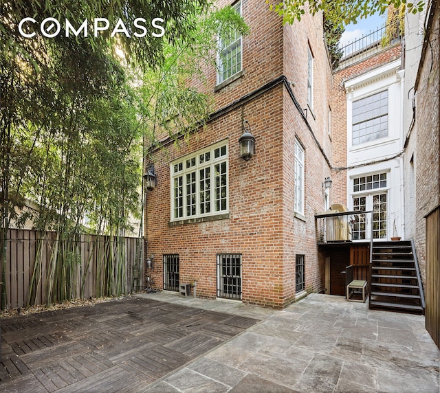 back of house with brick siding, stairway, a patio area, and fence