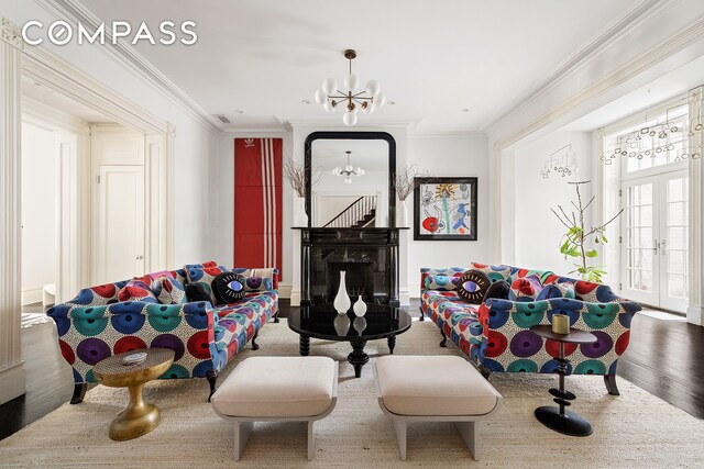 living area with wood finished floors, ornamental molding, french doors, and a chandelier