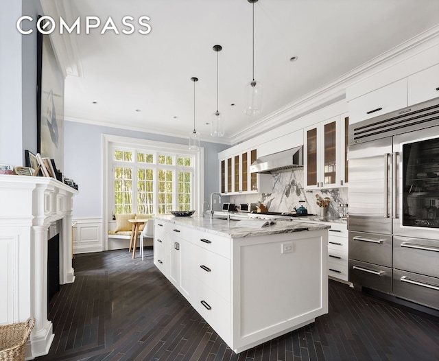 kitchen with a sink, decorative backsplash, wall chimney exhaust hood, and crown molding