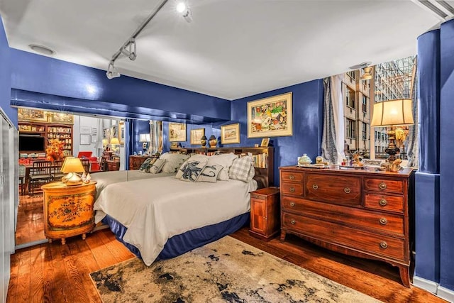 bedroom featuring hardwood / wood-style floors and track lighting