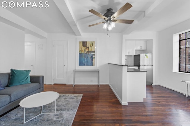 living room featuring ceiling fan, dark hardwood / wood-style flooring, radiator heating unit, and beamed ceiling