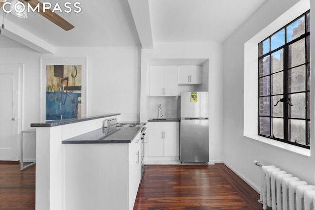 kitchen featuring white cabinetry, stainless steel fridge, radiator heating unit, and kitchen peninsula