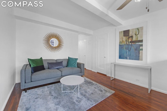 living room featuring ceiling fan, dark hardwood / wood-style floors, and beamed ceiling