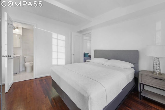 bedroom featuring beamed ceiling, dark hardwood / wood-style floors, and ensuite bath