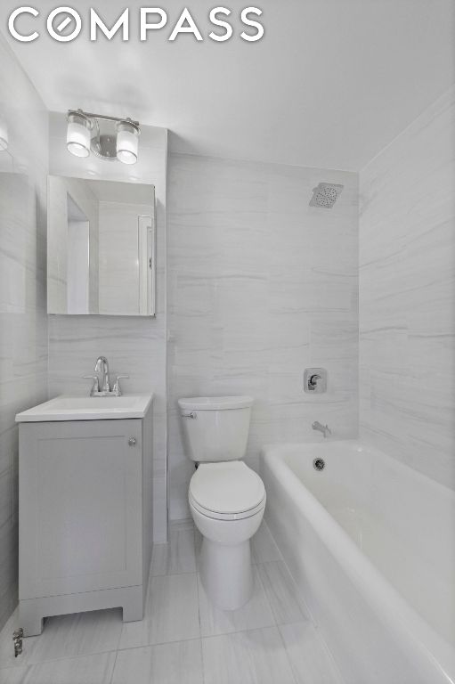 bathroom with toilet, vanity, and tile walls