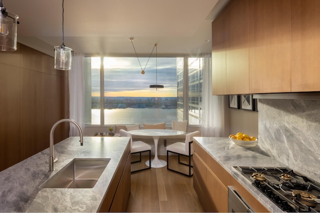 kitchen with a sink, modern cabinets, wood finished floors, gas cooktop, and light brown cabinets